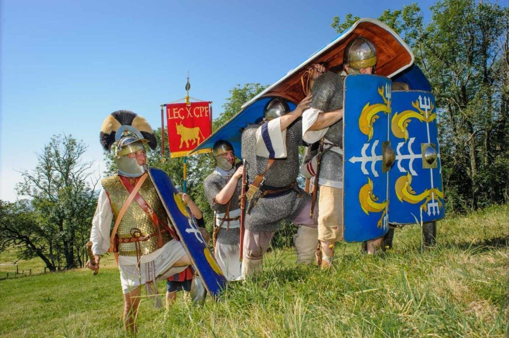 Menší oddíl legionářů kryjící se svými štíty proti přilétajícím střelám postupuje do kopce během menší šarvátky s Germány